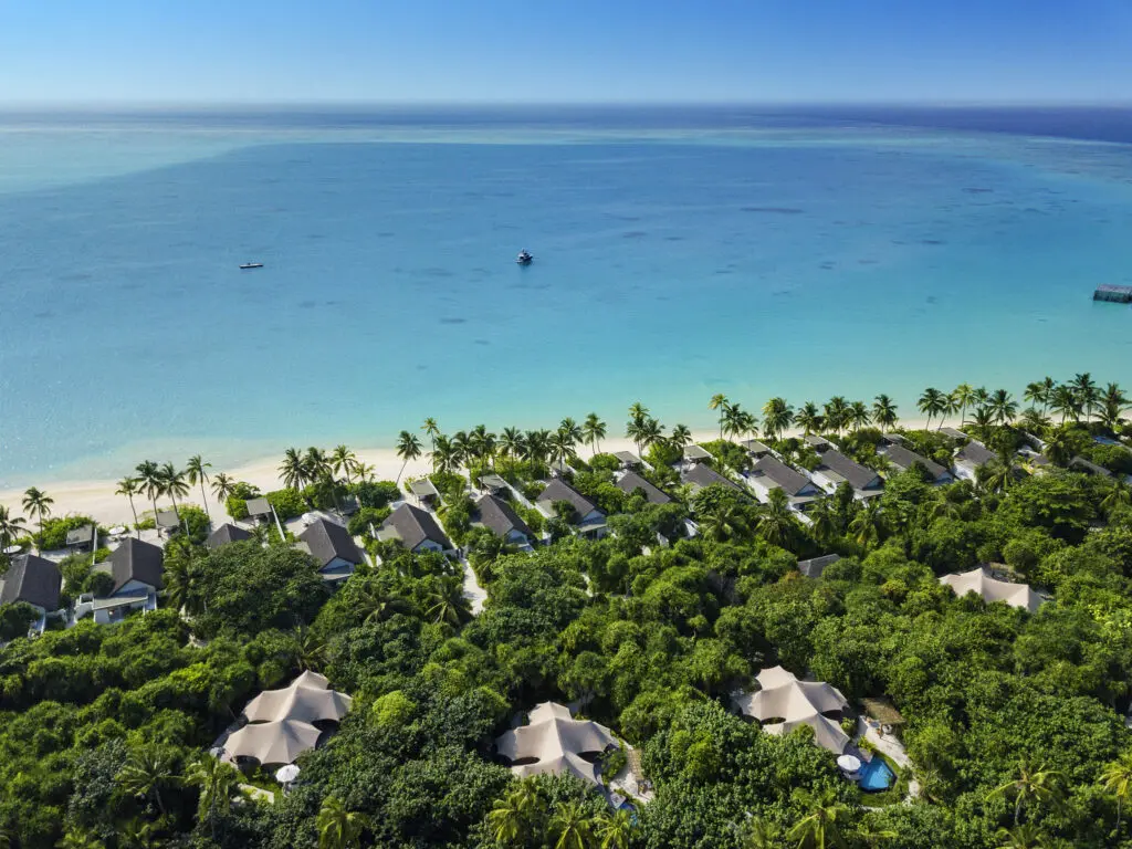 Luftaufnahme der Villen am Strand, umgeben von üppigem Grün und mit Blick auf das türkisfarbene Wasser im Sirru Fen Fushi Resort auf den Malediven