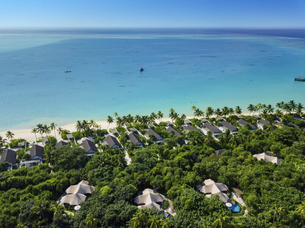 Aerial view of beachfront villas surrounded by lush greenery and overlooking the turquoise waters at Sirru Fen Fushi Resort in the Maldives